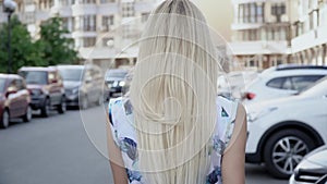 Blonde in a summer suit posing in the parking lot. Camera wiring. Women's walk