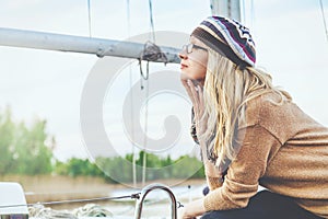 Blonde in sunglasses against backdrop of mast yacht