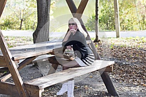 The blonde in sunglasses at a wooden table at the lake
