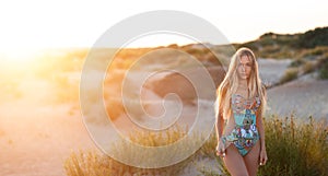 blonde in a swimsuit at sunset in the rays of a bright sun