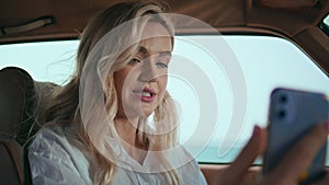 Blonde talking video call telephone in automobile close up. Woman videocalling
