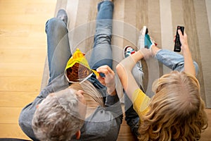 A blonde teen sitting on the floor with her dad and eating chips