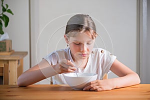 Blonde teenage girl eating cereal for breakfast. Lifestyle portrait.