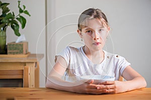 Blonde teenage girl eating cereal for breakfast. Lifestyle portrait.