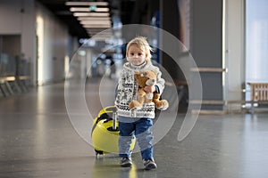 Blonde toddler boy with family, traveling with airplane, running at the airport