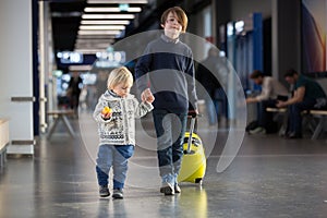 Blonde toddler boy with family, traveling with airplane, running at the airport