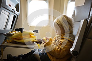 Blonde toddler boy, flying with airplane,enjoying the flight