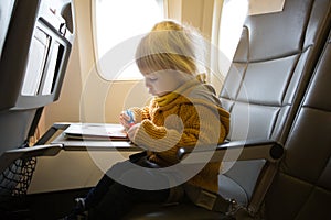 Blonde toddler boy, flying with airplane,enjoying the flight