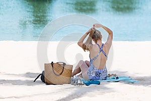 Blonde tourist girl in bikini relaxed and sunbathing on the beach