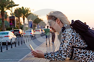 A blonde tourist girl in the Dubai resort area wanders around, taking selfies against the magnificent backdrop of modern