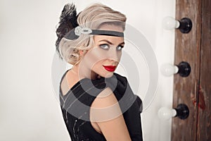 Blonde wavy hairstyle. Elegant woman portrait in retro style. Beautiful girl wears in vintage black dress and gloves. Hollywood