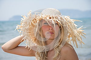 Blonde wearing straw hat on sunny beach