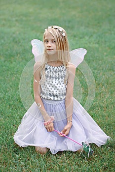 Blonde white Caucasian child kid girl with long hair wearing pink fairy wings and tutu tulle skirt holding magic wand