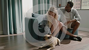 Blonde wife pets white dog and Afro-American husband looks