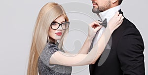Blonde woman adjusting tie bow for man