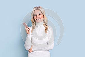 Blonde woman adult attractive beautiful smiling portrait with cellphone, mobile, cauasian and scandinavian girl on blue background photo