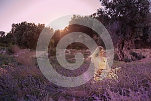 Blonde woman artist in yellow dress draws in the open air in lavender field