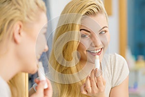 Woman in bathroom applying lip balm photo