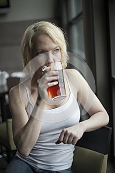 Blonde Woman with Beautiful Blue Eyes Drinking Glass of Pale Ale