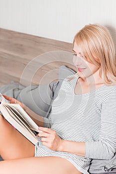 Blonde woman on the bed with book