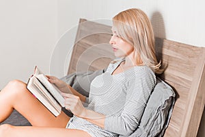 Blonde woman on the bed with book