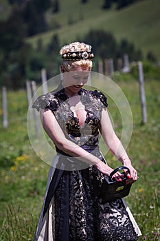 Blonde woman in black dirndl with bag and stylish hairstyle