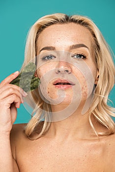 blonde woman with blemishes massaging face photo