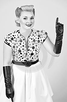 Blonde woman with blonde curl pointing up by hand in gloves