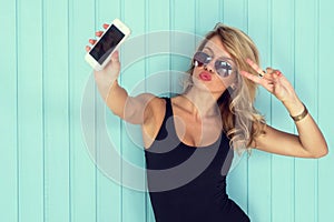 Blonde woman in bodysuit with perfect body taking selfie smartphone toned instagram filter