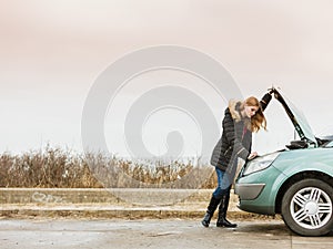 Blonde woman and broken down car on road