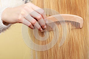 Blonde woman brushing her hair with comb