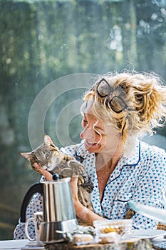 Blonde woman with a cat at breakfast time.