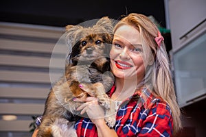 blonde woman in checkered shirt holding a dog in her arms