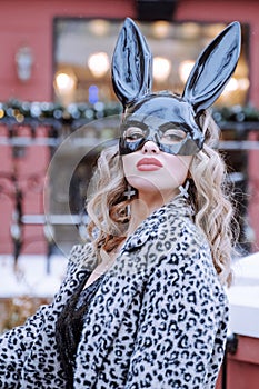 Blonde woman in coat and black bunny mask. Easter bunny concept. Naughty girl. vertical