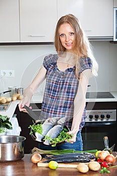 Blonde woman cooking lubina fish in frying pan photo