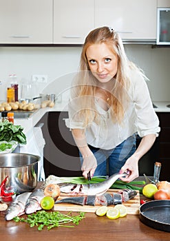 Blonde woman cutting raw fish photo