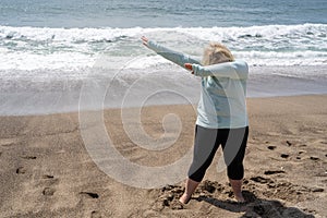 Blonde woman does a dabbing dance move on the beach
