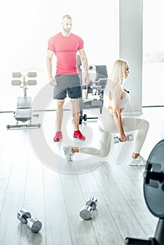 Blonde woman doing lunge exercise with personal trainer