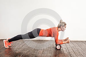 Blonde woman doing plank in foam roller