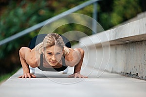 Blonde woman doing push ups outdoor.