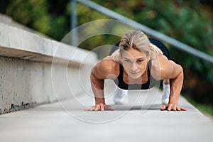 Blonde woman doing push ups outdoor.