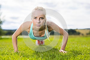 Blonde woman doing push-ups in the park