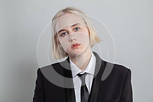 Blonde woman dressed in suit and tie poses on white background