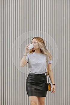 blonde woman drinking coffee walking on the street