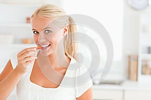 Blonde woman eating a slice of pepper