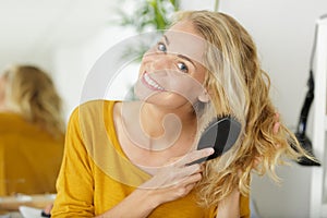 Blonde woman energetically brushing hair