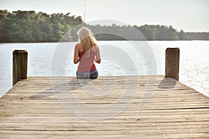 blonde woman fishes from dock