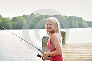 blonde woman fishes from dock