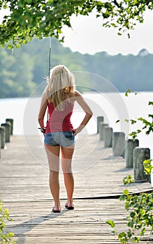 blonde woman fishes from dock