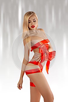 Blonde woman-gift with red ribbons on sexual body looking away